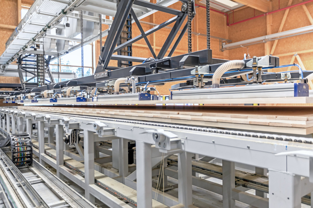 The second vacuum gantry places the press cake on the gluing and feeding table in front of the CLT press.